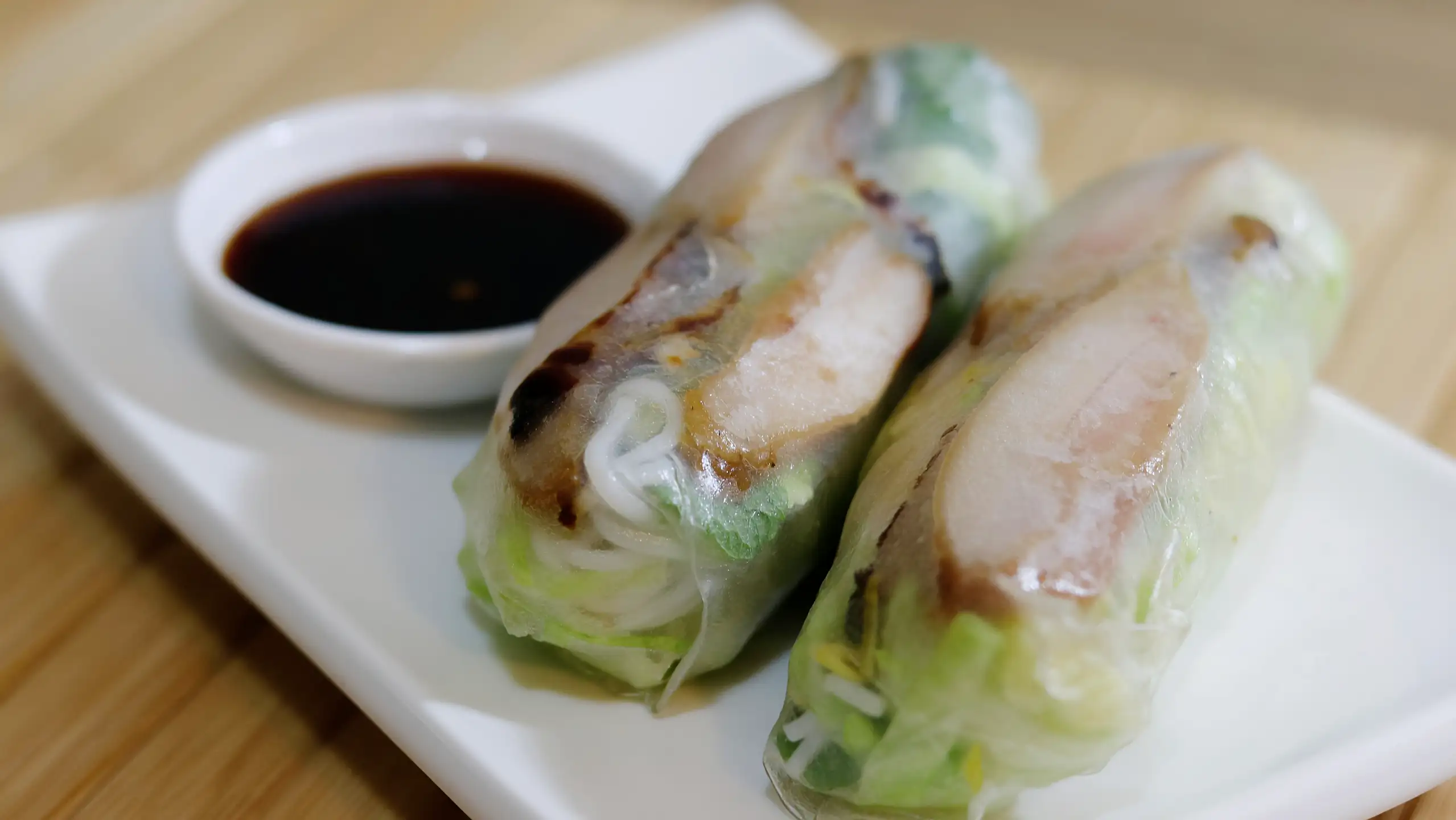 Chicken rice paper rolls served with dark dipping sauce.