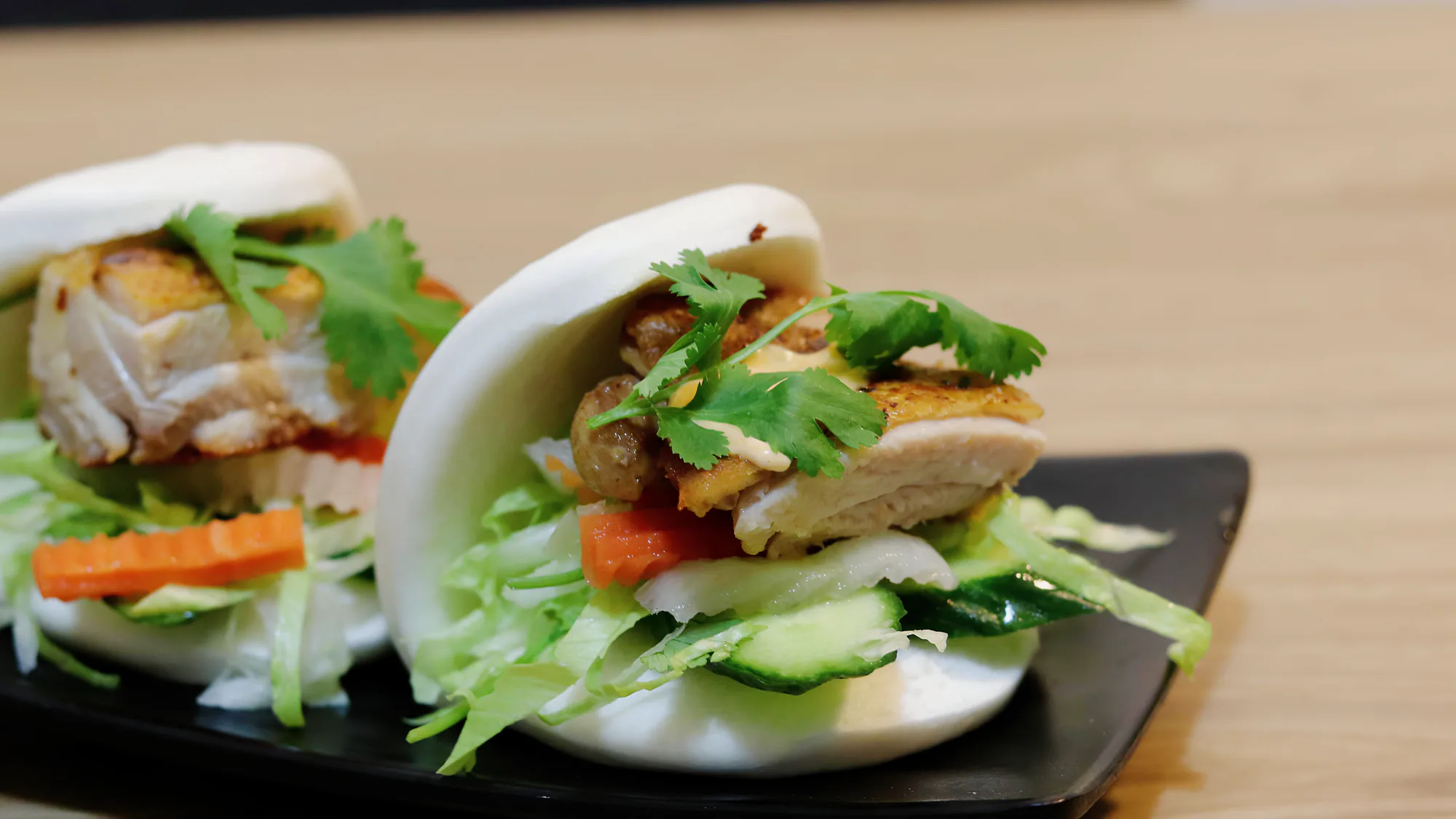 Crispy chicken bao buns arranged on a black serving plate.