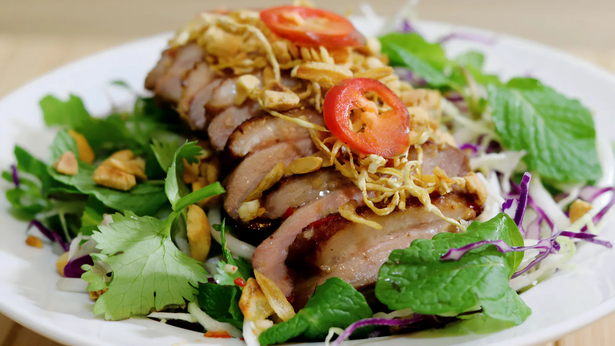 Grilled duck breast salad with mixed vegetables and herbs.